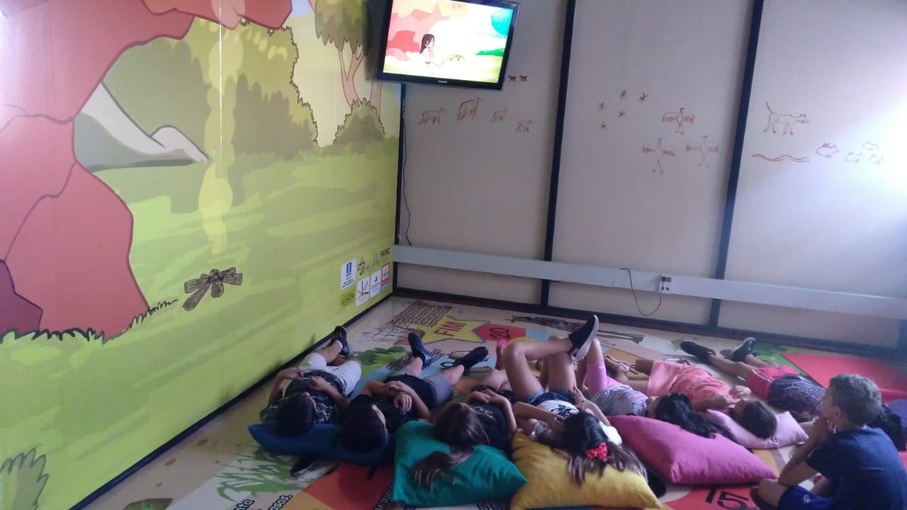 Área Lúdico-pedagógica 2 - Nas trilhas do passado arqueológico de MS – Crianças assistindo o vídeo Brincando de passado no museu